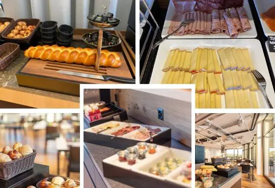 Mehrere Buffet-Tische zeigen eine Auswahl an Speisen für einen Macardo Brunch. Zu sehen sind Zopf, Brot, Käse, Fleisch, Joghurt und kleine Gläser mit Aufstrichen. Das Buffet ist in einem hellen Raum aufgebaut, Tische und Stühle stehen bereit.